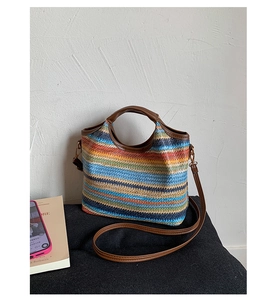 Detail of colorful woven bucket bag featuring brown leather handles and adjustable strap