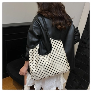 Polka dot pattern detail on a large capacity canvas tote bag with black piping accents