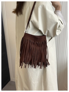 Detailed shot of a brown suede shoulder bag featuring long fringe and a slim strap