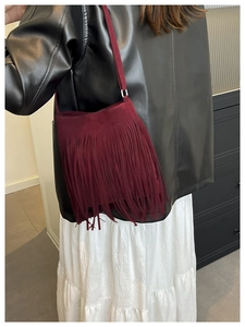 Vue latérale d'un sac à bandoulière vintage en daim bordeaux avec de longues franges