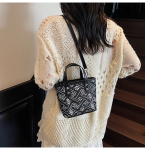 Detail of printed bucket bag with geometric patterns worn over beige knit sweater