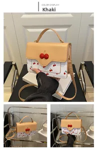Detail of khaki crossbody bag with cherry prints and a 3D red cherry decorative buckle