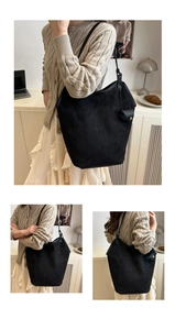 Detail of a large black faux suede tote bag with side pouch and leather shoulder straps