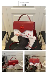 Detail view of a red and white cherry print crossbody bag with 3D cherry accents