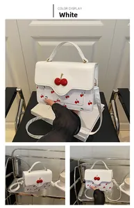 Detail view of white cherry print crossbody bag with cute 3D cherry clasp and handle