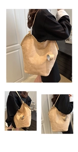 Detail view of khaki suede tote bag featuring smooth leather trim and decorative pendant