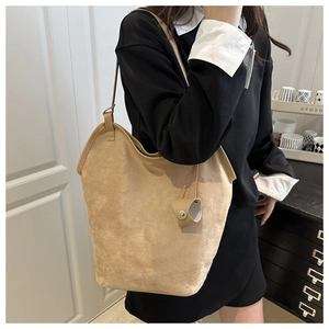 Detail of camel faux suede tote bag with slim shoulder strap and leather charm pendant