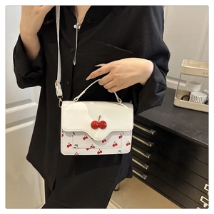Detail of cute cherry print crossbody bag with 3D cherry accents on white leather