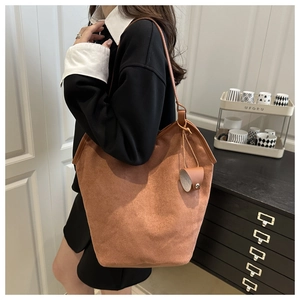 Detail of a large brown suede tote bag featuring a decorative side leather drawstring tie
