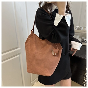 Brown faux suede tote bag with slim shoulder straps shown on a model in a minimal setting