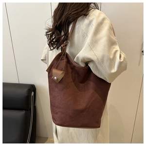 Detail of dark brown suede tote bag featuring a slouchy design and a small charm pouch