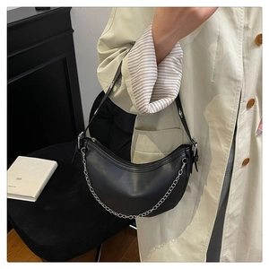 Detail of black leather crescent bag with silver chain strap and top zipper closure