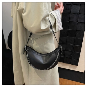 Detail of black crescent shoulder bag featuring silver chain and adjustable eyelet strap
