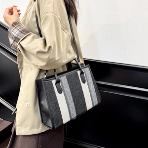 Fashion striped canvas tote bag with black leather straps shown on a model