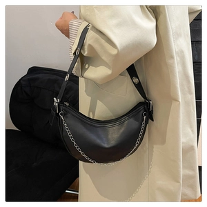 Detail view of black half-moon bag with silver chain and metal eyelet shoulder strap