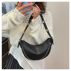 Detail of black crescent shoulder bag featuring silver chain and metal eyelet strap