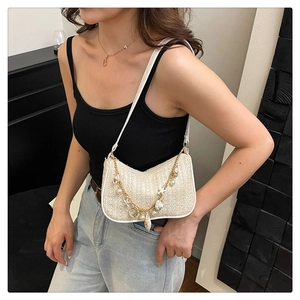 Detail of beige woven shoulder bag featuring gold chain with pearl and starfish charms