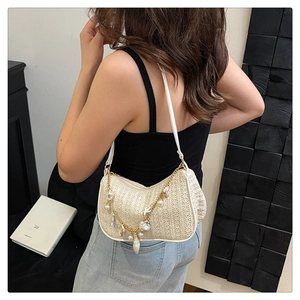 Detail of beige straw shoulder bag with gold chain featuring shells and pearls