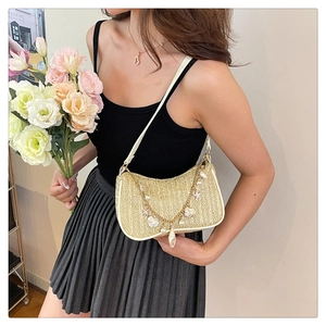 Detail of straw woven crossbody bag featuring pearl shell charms and a white shoulder strap