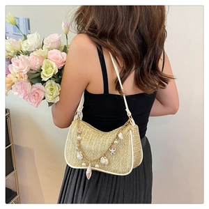 Detail of summer straw bag featuring pearl, seashell charms, and golden chain accessories