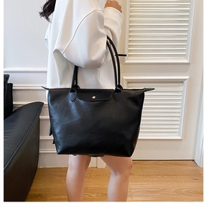 Detail of minimalist black nylon tote bag with leather flap and metallic snap closure