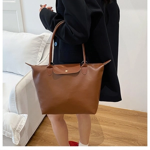 Close-up of brown faux leather tote bag showing handle details and metal snap button