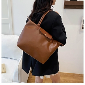 Detail view of the caramel brown tote bag showing smooth PU leather texture and metal snap button