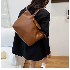 Detailed close-up of brown faux leather tote bag with flap closure and long handle straps