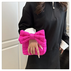 Detail of fuchsia quilted bow-shaped handbag with textured nylon stitching and vibrant color