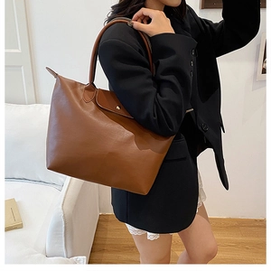 Close-up of large brown nylon tote bag with leather flap and gold button closure