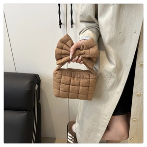 Detail of a brown quilted handbag featuring a large bow and soft polyester stitching