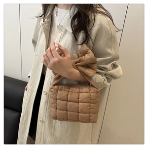 Close-up of brown quilted handbag with oversized bow detail on shoulder strap