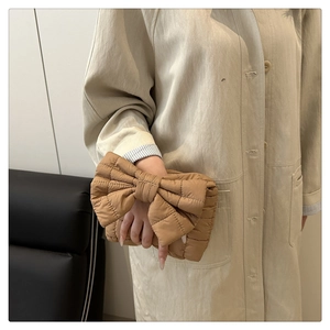 Detail of khaki quilted puffer handbag featuring a unique large bow design and grid stitching
