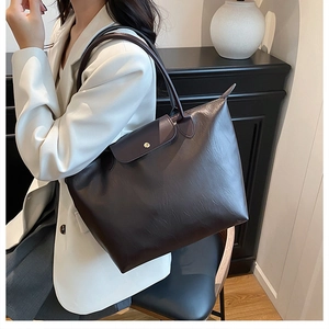 Close-up of the dark brown leather tote bag with a gold button flap and premium texture