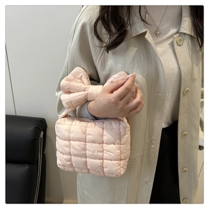 Close-up of light pink quilted handbag featuring a large elegant bow knot handle