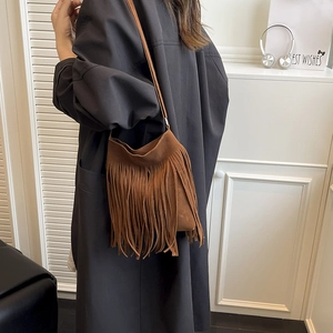 Sac seau chic en daim marron avec de longues franges porté par un mannequin pour un look décontracté