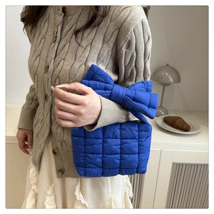 Dettaglio borsa trapuntata blu con grande fiocco e stile in maglia autunnale