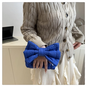Dettaglio di borsa trapuntata blu brillante con grande fiocco 3D mostrata sull'outfit