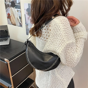 Elegant black crescent hobo shoulder bag with silver chain detail on a model in office