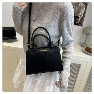 Detail of black crossbody bag with gold Fashion Bag lettering and adjustable strap