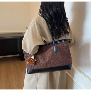 Detail of leopard print tote bag with plush charm on minimalist interior background