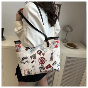 Dettaglio laterale di una borsa tote in tela bianca con graffiti urbani e tracolla in pelle