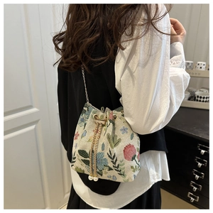 Detail of floral tapestry bucket bag with gold chain strap and pearl drawstring accents
