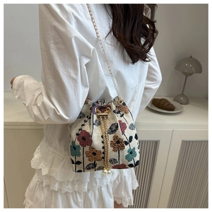 Detail of vintage floral drawstring bucket bag with gold chain and pearl tassel charm