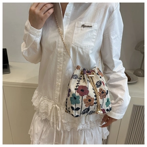 Detail of ethnic floral drawstring bucket bag with gold chain and pearl charms