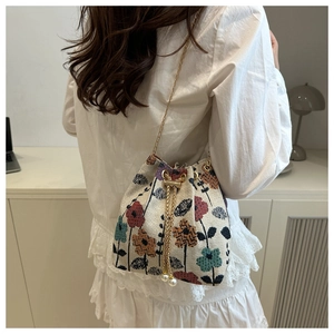 Detail of floral tapestry bucket bag featuring drawstring closure and pearl charm