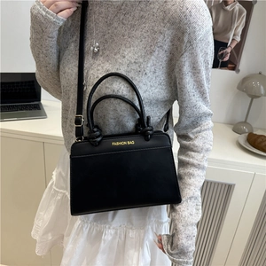 Large black leather tote with knot handles and gold lettering shown in a modern interior
