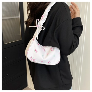 Detail view of floral hobo bag with pink rose patterns and adjustable bow strap on shoulder