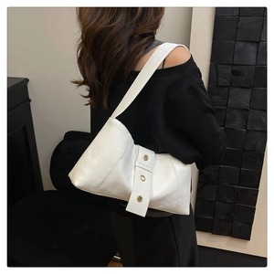 Detail shot of a white leather hobo bag with gold eyelet strap on a female model