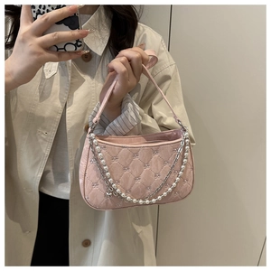 Detailed close-up of pink quilted shoulder bag with pearl chain and star pendant detail